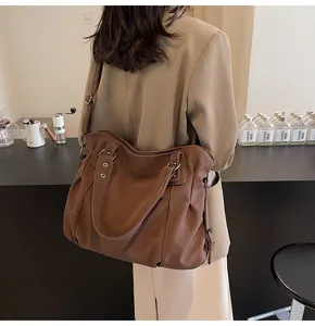 Grand sac à main en cuir marron porté à l'épaule dans une ambiance de café chaleureuse