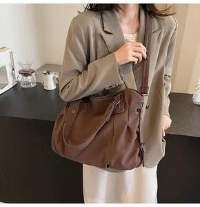 Détail du sac cabas en similicuir marron avec rivets argentés et large bandoulière