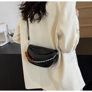 Detalle de bolso nube negro con doble correa de cadena plateada y cuentas marrones