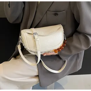 Detalle de bolso nube blanco roto con textura de ecocuero y correa de cadena plateada