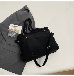 Détail d'un grand sac cabas noir avec rivets argentés sur un fond en tissu minimaliste