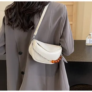 Detalle del bolso nube blanco con cadena plateada y detalles de cuentas de color ámbar