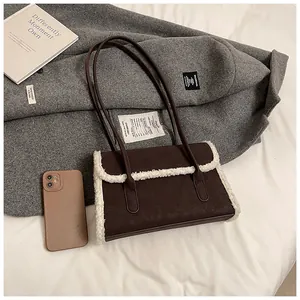 Détail du sac bandoulière en daim marron avec bordure en polaire sur un manteau chic