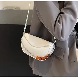 Detalle de bolso nube blanco roto con cuentas de ámbar y correa de cadena plateada