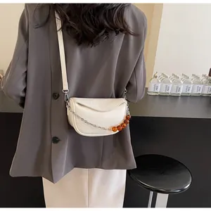 Detalle del bolso nube blanco crema con cadena de cuentas de ámbar y textura de cuero plisado