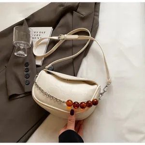 Detalle de bolso nube blanco crema con cadena de cuentas de ámbar y cuero plisado suave