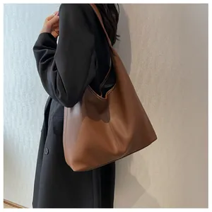 Detailed view of brown leather tote bag with lychee texture worn with black blazer