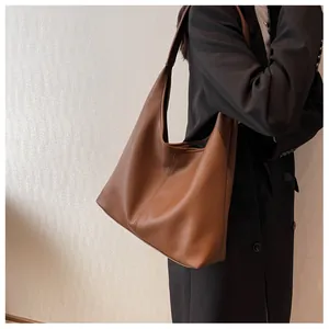Close-up of brown pebbled leather tote bag showing soft texture and vertical stitching