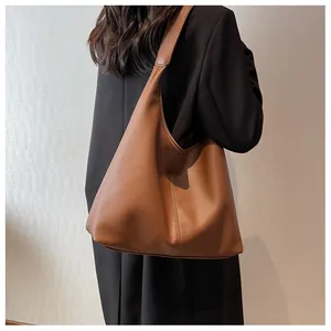 Brown lychee leather tote bag shown on shoulder featuring wide strap and vertical stitching
