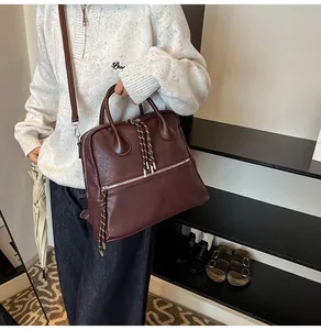 Dettaglio dello zaino bordeaux vintage con cerniera decorata da corda intrecciata