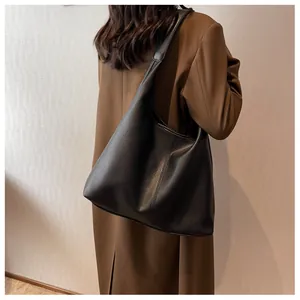 Side view of large black pebble leather tote bag worn with stylish long winter coat
