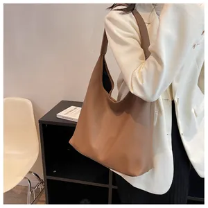 Detail of caramel leather tote bag showing soft lychee texture and wide shoulder strap