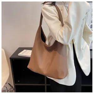 Brown lychee leather hobo bag styled on model with a white tweed jacket for a chic look