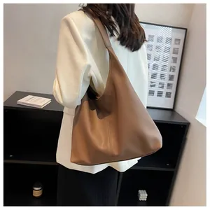 Rear view of a model wearing a large tan leather tote bag with wide shoulder straps