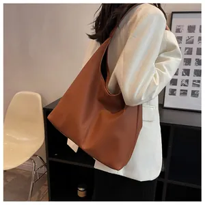 Caramel lychee grain leather tote bag shown on shoulder in a minimalist indoor setting