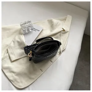 Détail du sac seau noir en cuir matelassé avec sangle jacquard et plaque logo métal