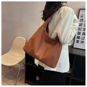 Brown leather hobo tote bag worn on shoulder showing its large capacity and drape
