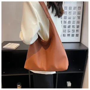 Brown large capacity leather tote bag worn by a model in a minimalist setting