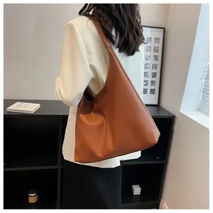 Brown leather hobo tote bag worn over shoulder showing textured finish and minimal style