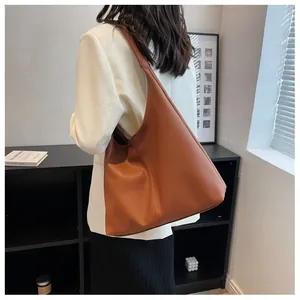 Side view of caramel large capacity leather tote bag worn as a shoulder bag