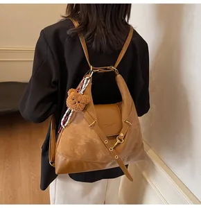 Detail showing brown tote bag with suede stitching, bear charm, and striped silk scarf