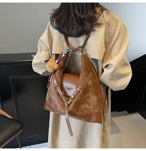 Detail of vintage brown tote bag with suede patchwork and a cute teddy bear charm