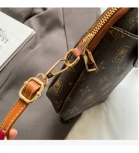 Close-up of golden hardware and vintage monogram pattern on small brown shoulder bag