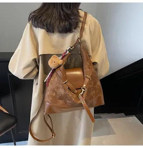 Detail of a brown matte leather tote bag worn with a khaki trench coat for a chic look
