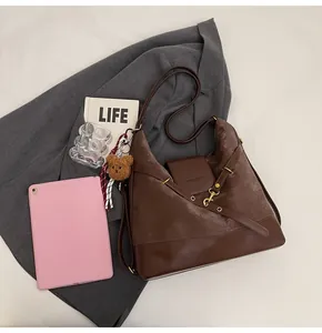 Detail of dark brown matte tote bag with leather patchwork, buckle, and teddy charm