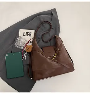Detailed flat lay of a large brown suede tote bag with a cute bear plush keychain