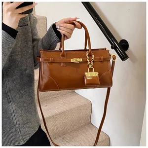 Detail der dunkelbraunen glänzenden Ledertasche mit goldenem Drehverschluss und Anhänger