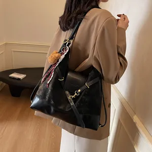 Black large tote bag with matte patchwork and plush bear pendant shown on model