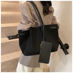 Detail van grote zwarte suède shopper met bijpassende etui en slanke schouderbanden