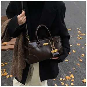 Detaillierte Nahaufnahme der dunkelbraunen Glanztasche mit goldenen Beschlägen und Schloss