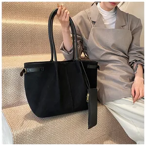 Detail van zwarte tote bag met matte textuur, zijgesp en bijpassend klein tasje