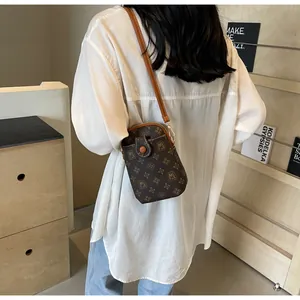 Model view of a vintage monogram mobile phone bag with brown leather strap and classic pattern