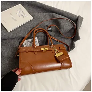 Detail der braunen Vintage-Einkaufstasche mit Metallschnalle und Mini-Taschenanhänger-Zubehör