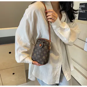 Close-up of vintage brown crossbody phone bag with MJ monogram print on the shoulder