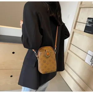 Detail of vintage brown monogram mini crossbody phone bag with gold zipper and button pocket