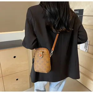 Brown monogram crossbody phone bag styled on a model wearing a black blazer