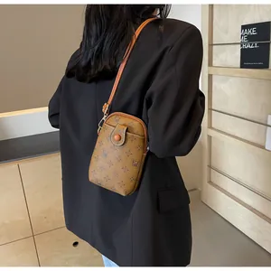 Detail of a vintage-style brown leather mini crossbody bag with a slim strap on a model