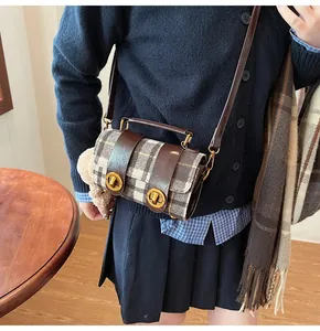 Dettaglio di una borsa a tracolla vintage a quadri con finiture in pelle e fibbie oro