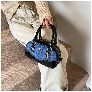Chic blue denim and black faux leather bowling bag with metallic logo on textured surface