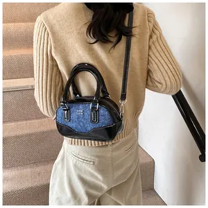 Detail of vintage denim and black patent leather bowling bag with contrast stitching