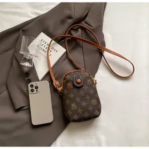 Detail of vintage brown monogram phone bag with elegant gold patterns and slim strap