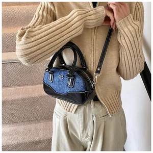 Fashionable mini bowling bag in black patent leather and denim on a stylish model