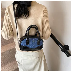 Detail of blue denim and black leather boston bag shown on model for size and fit reference