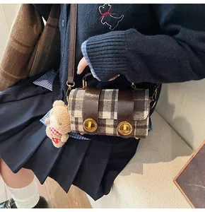 Dettaglio della borsa a quadri con finiture in pelle marrone e ciondolo a forma di orsetto