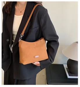 Detail of warm brown suede shoulder bag with metallic plaque and slim strap