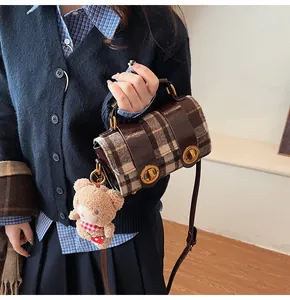 Dettaglio della borsa a quadri con chiusure dorate e ciondolo a forma di orsetto peluche
